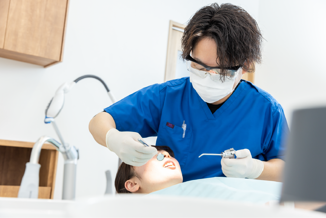 患者様の治療を行う院長と、患者様の口元に光を当てるスタッフ